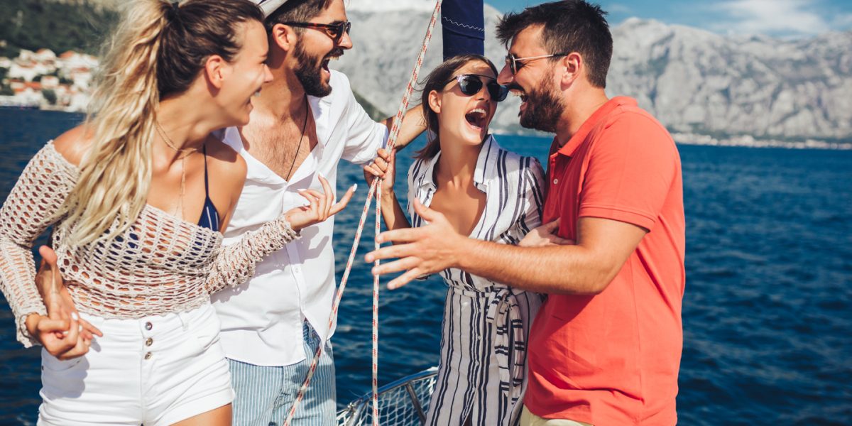 Smiling friends sailing on yacht - vacation, travel, sea, friendship and people concept